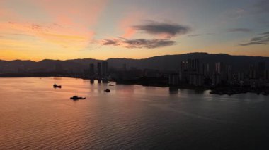 Gökyüzünden George Town kıyı şeridinin hava görüntüsü. Gemiler, siluetler ve gün batımının yansımaları..