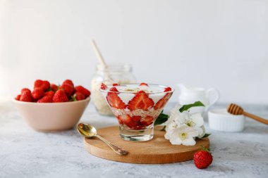 Taze çilekli yulaf ezmeli tatlı. Gri bir masada taze meyve ve yoğurtla çilekli sağlıklı bir kahvaltı. Panna Cotta. Doğru, doğal beslenme. Mesaj için yer var. Durgun hayat
