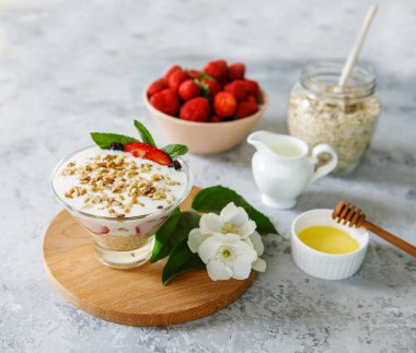 Taze çilekli yulaf ezmeli tatlı. Gri bir masada taze meyve ve yoğurtla çilekli sağlıklı bir kahvaltı. Panna Cotta. Doğru, doğal beslenme. Mesaj için yer var. Durgun hayat