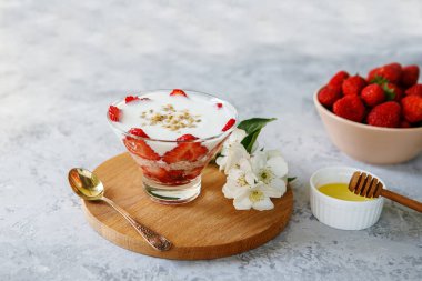Taze çilekli yulaf ezmeli tatlı. Gri bir masada taze meyve ve yoğurtla çilekli sağlıklı bir kahvaltı. Panna Cotta. Doğru, doğal beslenme. Mesaj için yer var. Durgun hayat