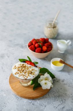Taze çilekli yulaf ezmeli tatlı. Gri bir masada taze meyve ve yoğurtla çilekli sağlıklı bir kahvaltı. Panna Cotta. Doğru, doğal beslenme. Mesaj için yer var. Durgun hayat
