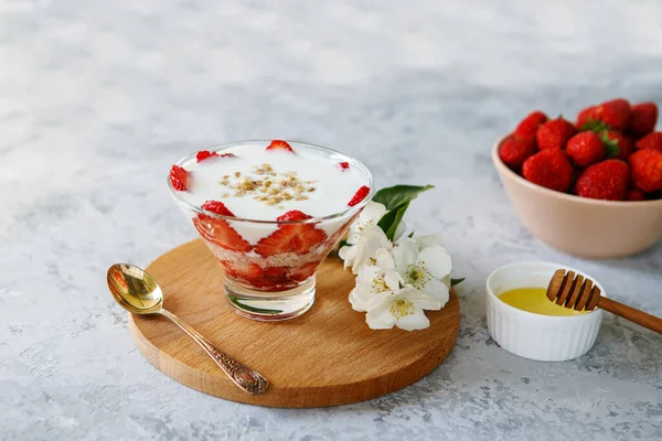 Taze çilekli yulaf ezmeli tatlı. Gri bir masada taze meyve ve yoğurtla çilekli sağlıklı bir kahvaltı. Panna Cotta. Doğru, doğal beslenme. Mesaj için yer var. Durgun hayat