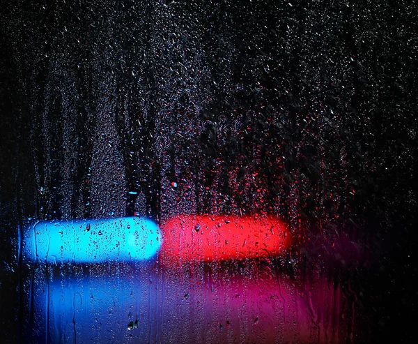 Janela e gotas de água, luzes de emergência no fundo — Fotografia de Stock