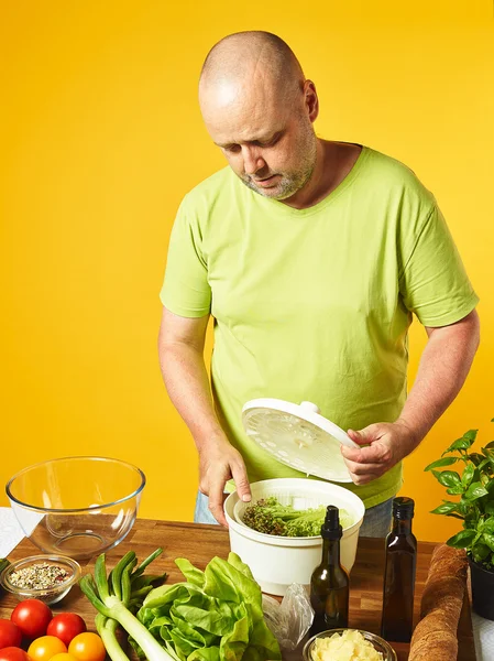 Homem de meia-idade cozinhar salada fresca — Fotografia de Stock