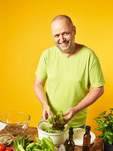 Mann mittleren Alters kocht frischen Salat Stockfoto