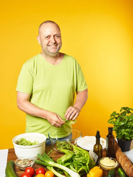 Mann mittleren Alters kocht frischen Salat lizenzfreie Stockfotos