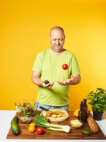 Mann mittleren Alters kocht frischen Salat Stockbild