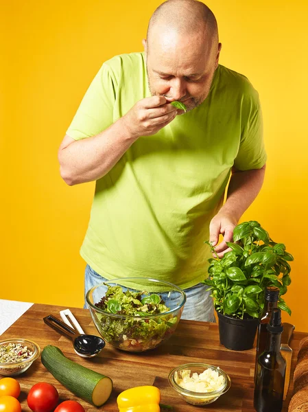 Homme d'âge moyen cuisiner une salade fraîche Photo De Stock