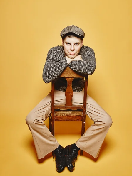 Expressive man sits on the chair and 70's look theme — 스톡 사진