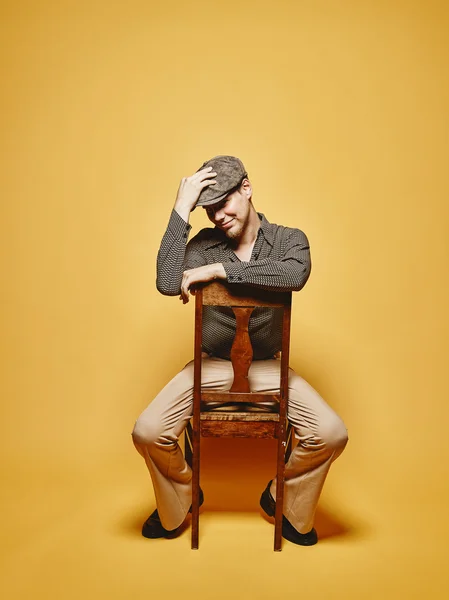 Expressive man sits on the chair and 70's look theme Εικόνα Αρχείου