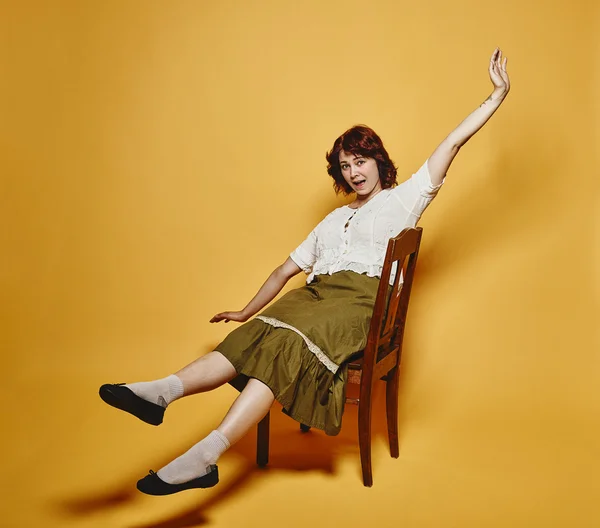 Donna espressiva si siede sulla sedia e 70 's look tema Fotografia Stock