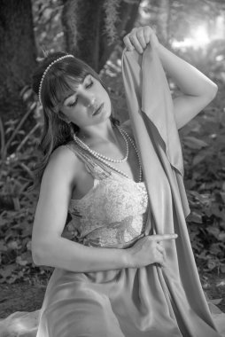 Güzel, genç, esmer, yarım boyda, ağaçlar ve doğa arasında düşünen bir kız.