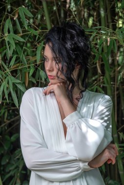 Güzel, genç, esmer, yarım boyda, ağaçlar ve doğa arasında düşünen bir kız.