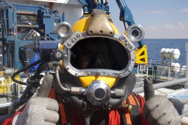 Denizaşırı sektörde çalışan kask takan profesyonel ticari dalgıç.