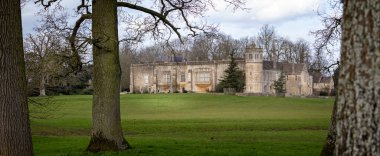 Tarihsel Lacock Manastırı 'nın panoramik görüntüsü 15 Mart 2021' de Lacock, Wiltshire, İngiltere 'nin güneyindeki ağaçların arasından geçiyor.