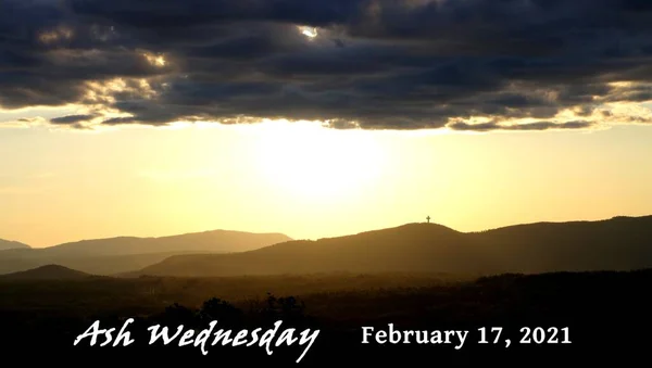 ash wednesday somber landscape scene with a cross on a distant hill and ash wednesday date of february 17th, 2021