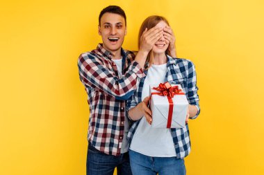 Genç aşık bir çift, bir erkek sürpriz yapar, sarı arka plandaki bir kadına hediye verir. Sevgililer Günü
