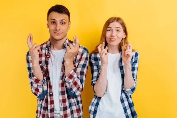 Young Couple Man Woman Praying Crossed Fingers Yellow Background — Stock Photo, Image