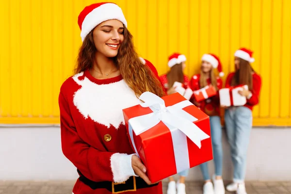 Schöne Lächelnde Junge Frau Mit Weihnachtsmann Hut Und Weihnachtsgeschenk Vor — Stockfoto