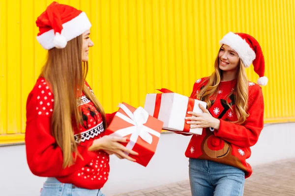 Duas Mulheres Jovens Sorridentes Camisolas Vermelhas Chapéus Papai Noel Dar — Fotografia de Stock