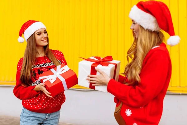 Duas Mulheres Jovens Sorridentes Camisolas Vermelhas Chapéus Papai Noel Dar — Fotografia de Stock