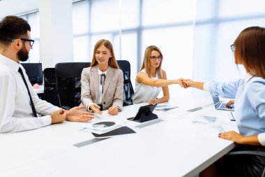 Ofis masasında iş arkadaşlarıyla birlikte otururken çalışan ve iletişim kuran gençlerden oluşan bir ekip.