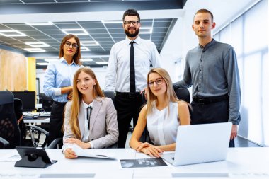 Ofiste çalışan takım bir arada ve gülümsüyor.