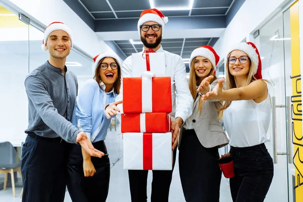 Noel 'i ofiste kutlarken Noel Baba şapkası takan iş adamları.
