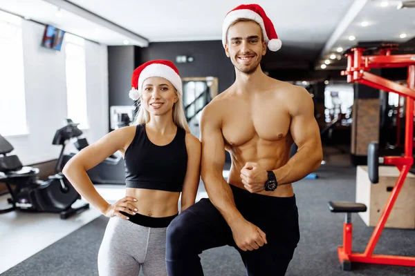 Glada Sportiga Par Santa Claus Hattar Sportkläder Visa Muskler Gymmet — Stockfoto