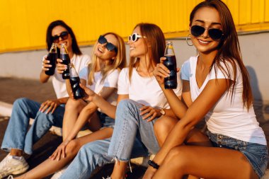 Güneş gözlüklü, gülümseyen genç kadınlar güneşli yaz gününde sınırda otururlar.