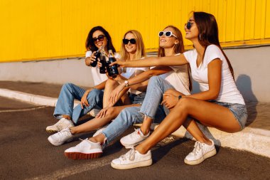 Mutlu gençler, yaz aylarında sarı duvarlara karşı birlikte vakit geçirdikleri için kadehlerini içkiyle tokuşturuyorlar.