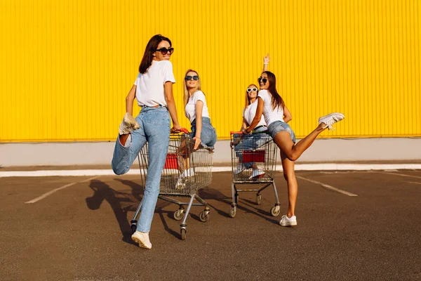 Mulheres Jovens Amigos Passeio Carrinho Compras Cidade Contra Parede Amarela — Fotografia de Stock