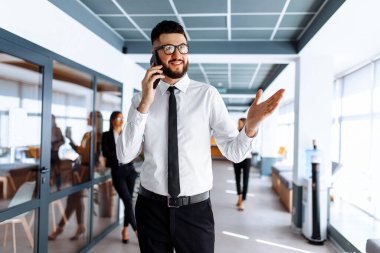 Ofiste cep telefonuyla konuşan mutlu bir işadamı.