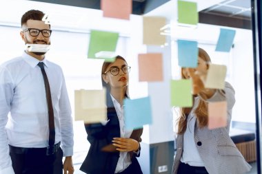 Parlak modern ofiste stratejik oturum sırasında beyaz tahtada takım oluşturan bir grup iş adamı.