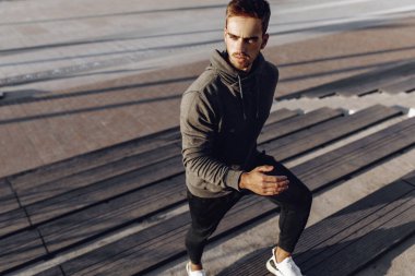 Spor giyimli genç bir adam, şehir merdivenlerinde spor yaparken koşuyor, spor yapıyor, sağlıklı bir yaşam sürüyor.
