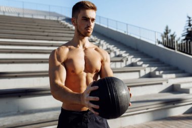 Topla egzersiz yapan kaslı sporcu, dışarıda topla spor yapan sporcu.