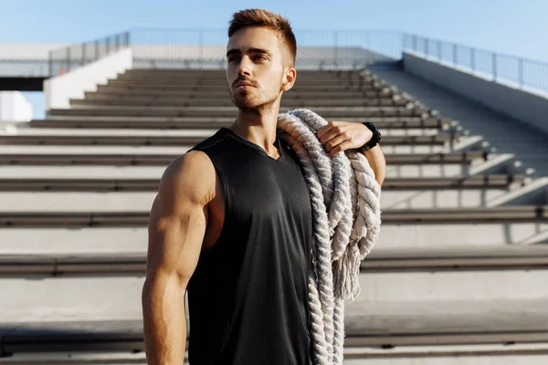 Sporty young man doing fitness workout outdoors, muscular man using two fighting ropes, sport, motivation
