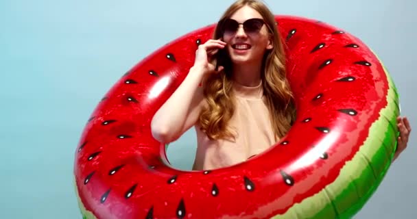 Приваблива усміхнена дівчина в купальнику, а літній капелюх тримає надувний — стокове відео