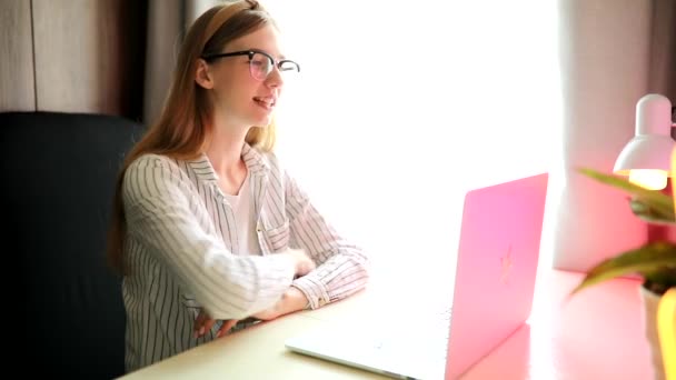 Jeune femme souriante avec des lunettes communiquant avec un client via un ordinateur portable — Video