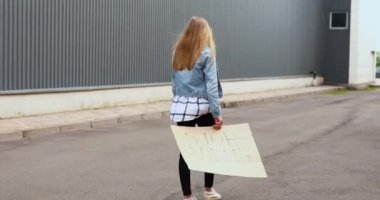 Tıbbi koruyucu maskeli bir kadın üzerinde şöyle yazan bir karton levha tutuyor: