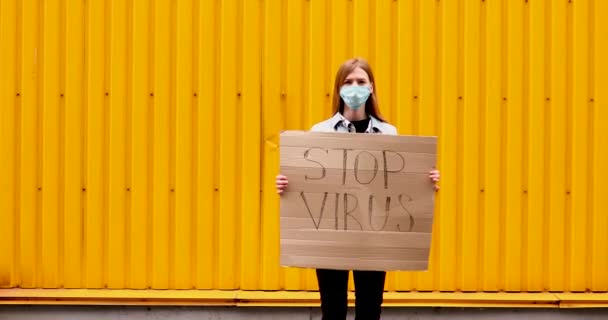 Woman in a medical protective mask holds a cardboard placard with the words — Stock Video