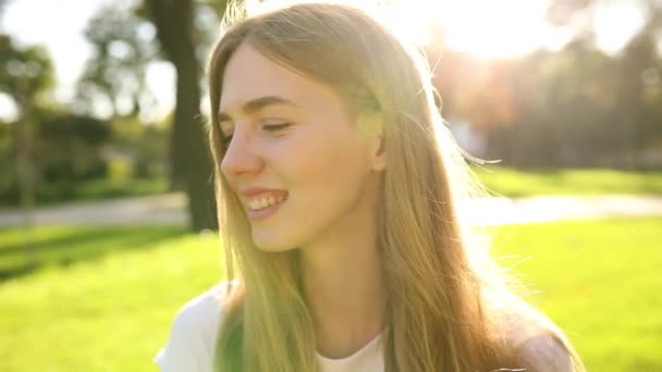 Krásná mladá žena se usmívá a dívá se do parku, ulice portrét usměvavé dívky, šťastná veselá dívka se směje v parku — Stock video