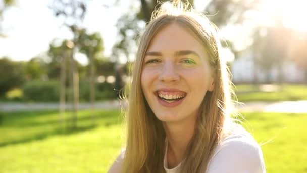 Young woman smiling and looking in the park, street portrait of a smiling girl, happy cheerful girl laughing in the park — Stock Video