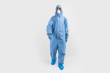Koruyucu giysili, gözlüklü, maskeli ve eldivenli erkek doktor, beyaz arka plan, koronavirüs salgını konsepti