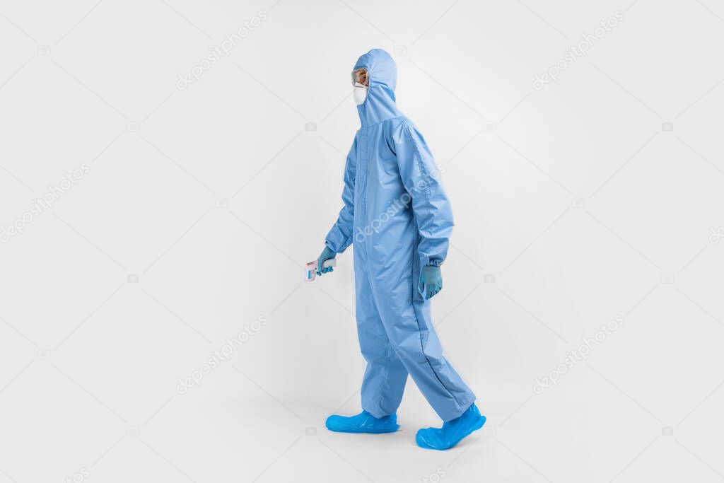 male doctor wearing protective clothing, glasses, mask and gloves, with a non-contact thermometer to measure temperature, on a white background, coronavirus epidemic concept