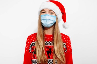 Çekici mutlu genç Noel Baba kadın Noel şapkası takıyor, tıbbi maske takıyor, Coperid-19 Coronavirus virüsünden korunuyor, beyaz arka planda, yeni yıl bayramını kutluyor.