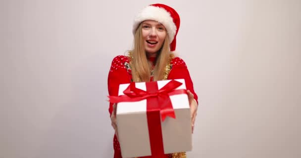Счастливая молодая женщина в рождественской шляпе Санта Клауса держа большую подарочную коробку с новогодним подарком изолированы на белом фоне — стоковое видео