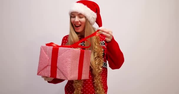 Atrakcyjne młoda kobieta sobie Boże Narodzenie Santa Claus kapelusz gospodarstwa duże pudełko z nowego roku obecny izolowany na białym tle — Wideo stockowe