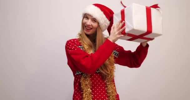 Glückliche junge Frau trägt Weihnachtsmann Hut hält große Geschenkbox mit Neujahrsgeschenk isoliert auf weißem Hintergrund — Stockvideo