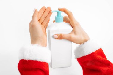 Covid-19 Santa Claus, hands of Santa Claus, applying disinfectant alcohol gel on his hands, over white background. Hand disinfection to prevent a viral epidemic
